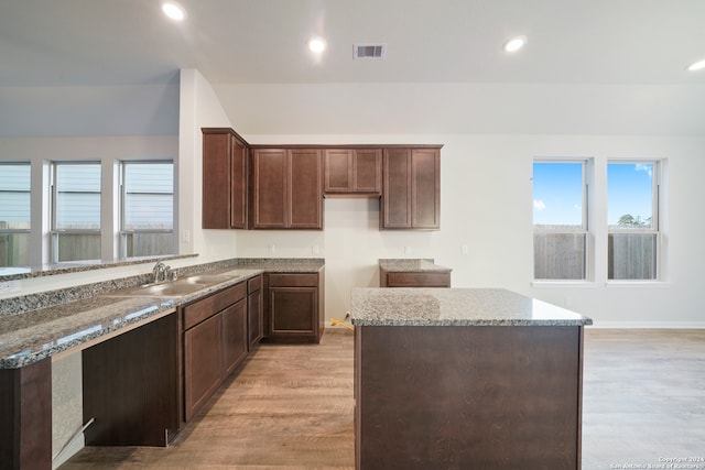 kitchen featuring stone counters, a center island, light hardwood / wood-style flooring, and sink