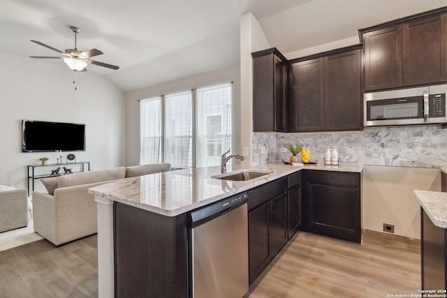 kitchen with kitchen peninsula, stainless steel appliances, vaulted ceiling, and sink