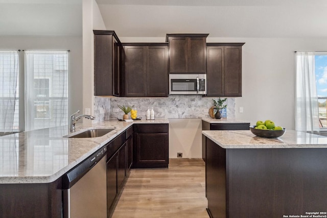 kitchen featuring decorative backsplash, stainless steel appliances, light stone counters, and sink