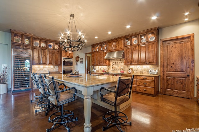 kitchen with decorative light fixtures, sink, a breakfast bar area, light stone counters, and a spacious island