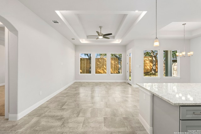 interior space with a tray ceiling and ceiling fan with notable chandelier