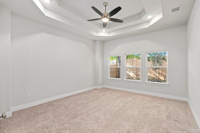 carpeted spare room featuring a tray ceiling and ceiling fan