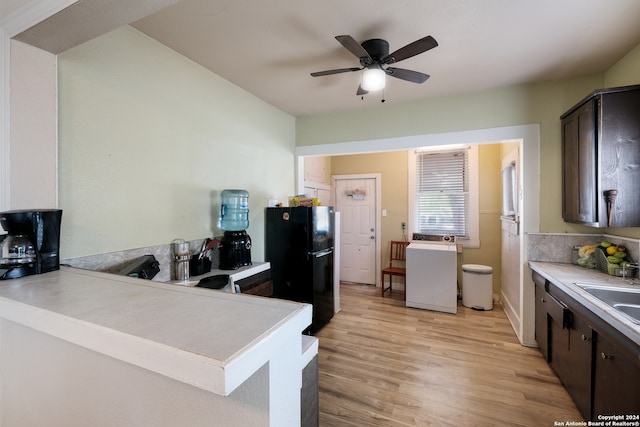 kitchen featuring black fridge, dark brown cabinetry, washer / clothes dryer, light hardwood / wood-style flooring, and ceiling fan