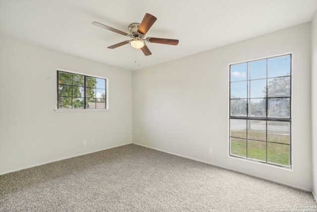 carpeted spare room featuring ceiling fan and plenty of natural light