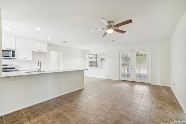 kitchen with sink, appliances with stainless steel finishes, light stone countertops, white cabinets, and french doors