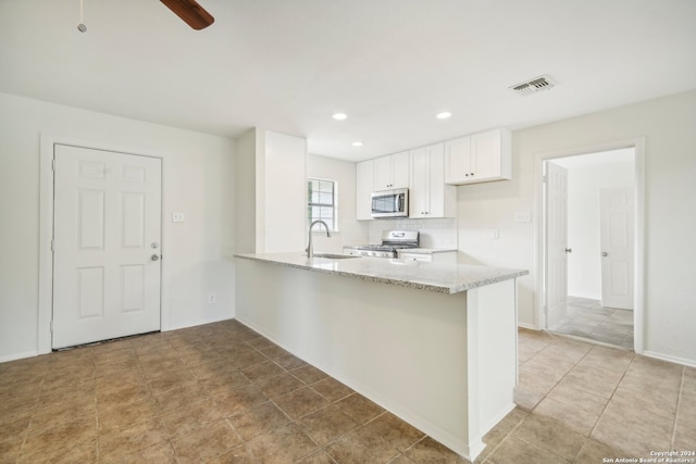 kitchen featuring stainless steel appliances, sink, light stone counters, kitchen peninsula, and white cabinets