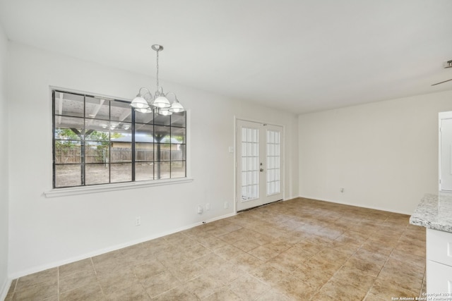 spare room with french doors and an inviting chandelier