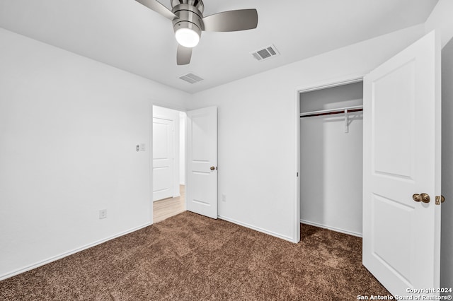 unfurnished bedroom featuring dark colored carpet, a closet, and ceiling fan