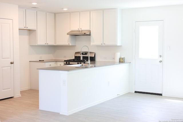 kitchen featuring gas stove, kitchen peninsula, white cabinetry, and light wood-type flooring