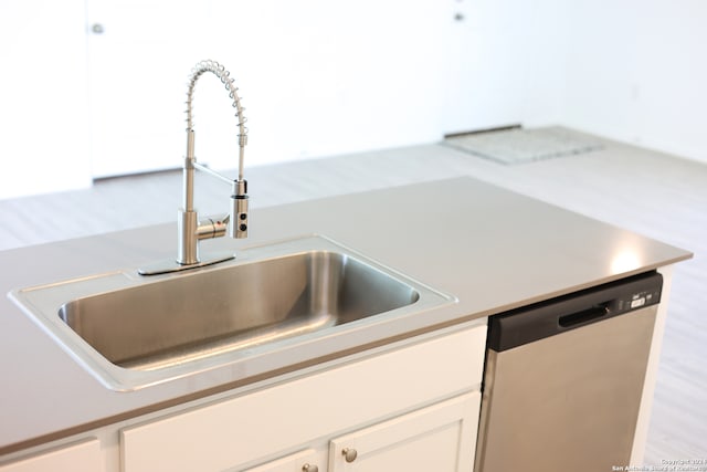 kitchen featuring white cabinets, light hardwood / wood-style flooring, stainless steel dishwasher, and sink