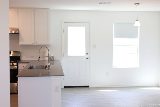 kitchen with hanging light fixtures, sink, white cabinets, plenty of natural light, and stainless steel range with gas stovetop