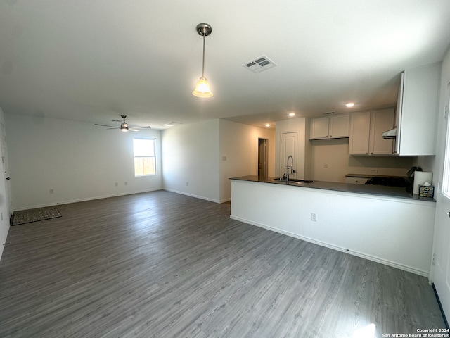 kitchen with ceiling fan, sink, kitchen peninsula, decorative light fixtures, and hardwood / wood-style flooring