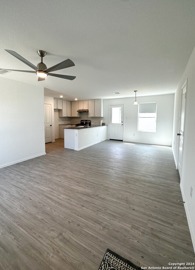 unfurnished living room with hardwood / wood-style floors, ceiling fan, and sink