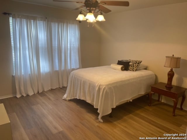 bedroom featuring wood-type flooring, ceiling fan, and multiple windows