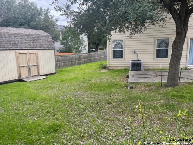 view of yard featuring a storage unit and central AC