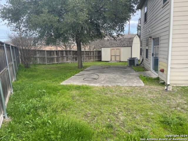 view of yard featuring central AC unit, a patio, and a storage unit