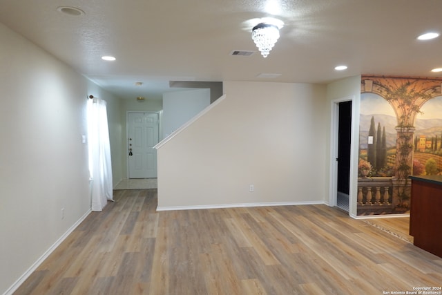 spare room featuring a notable chandelier and light wood-type flooring