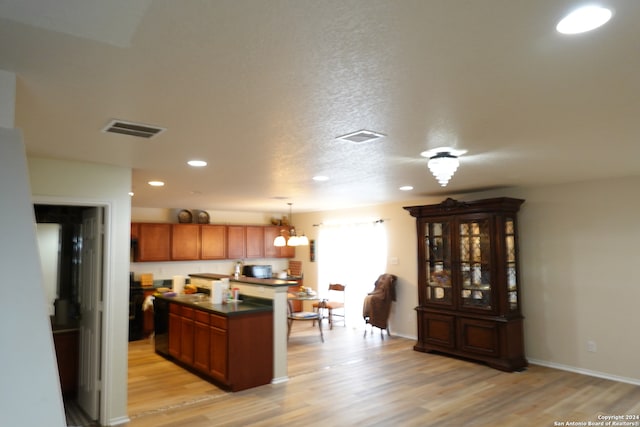 kitchen with a kitchen island, a chandelier, decorative light fixtures, a textured ceiling, and light wood-type flooring