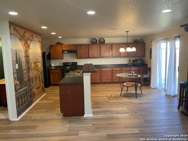 kitchen with a notable chandelier, decorative light fixtures, black appliances, and light hardwood / wood-style flooring