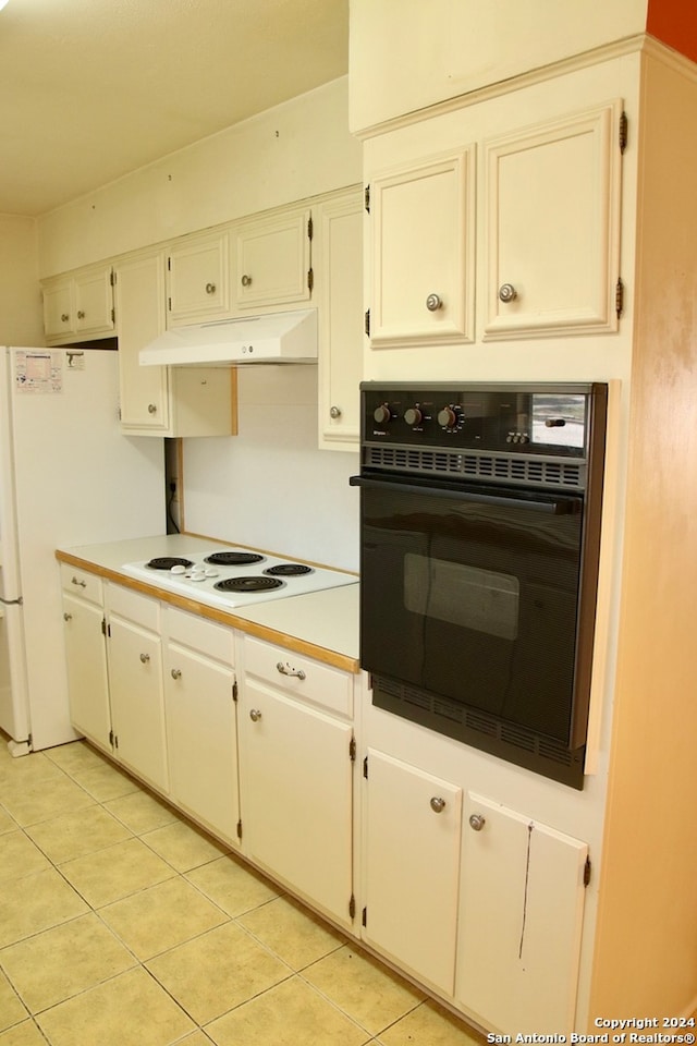 kitchen featuring light tile flooring, white electric stovetop, white cabinets, and black oven