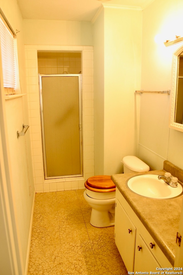 bathroom with toilet, a shower with shower door, oversized vanity, crown molding, and tile floors