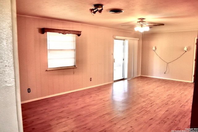 spare room with wood-type flooring, ceiling fan, and a healthy amount of sunlight