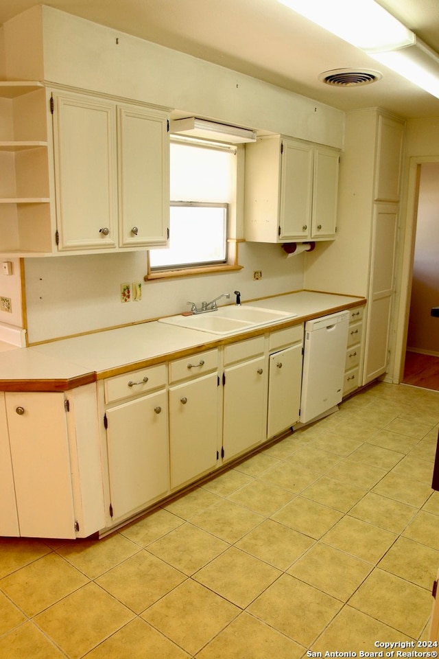 kitchen with light tile flooring, white dishwasher, white cabinets, and sink