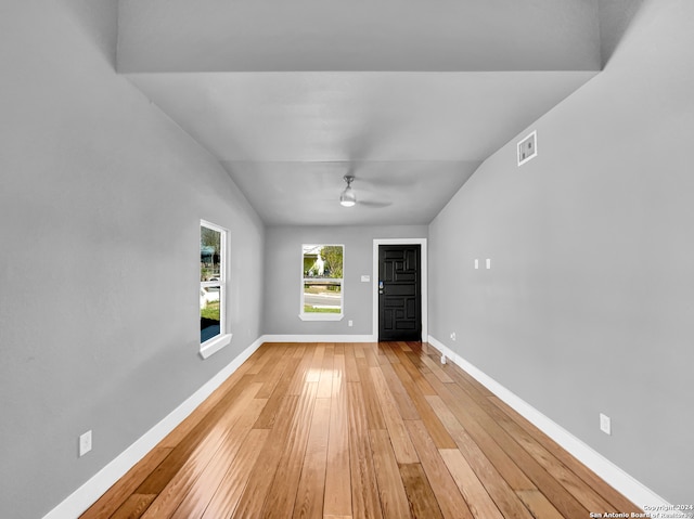 empty room with ceiling fan, light wood-type flooring, and vaulted ceiling