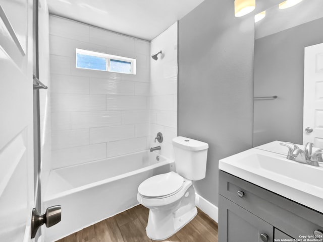 full bathroom with toilet, vanity, tiled shower / bath, and hardwood / wood-style floors