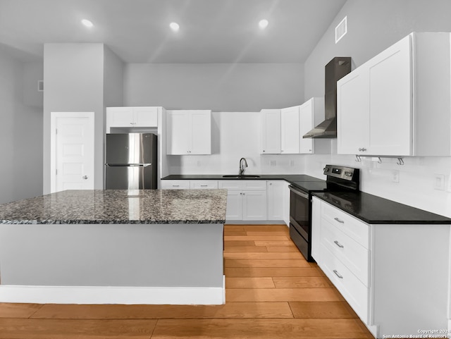 kitchen with light hardwood / wood-style floors, stainless steel appliances, tasteful backsplash, wall chimney exhaust hood, and white cabinetry