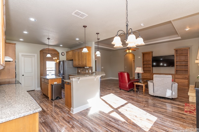 kitchen featuring a tray ceiling, kitchen peninsula, dark hardwood / wood-style floors, and stainless steel fridge