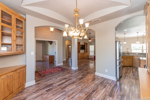 dining space featuring ceiling fan with notable chandelier, dark wood-type flooring, and vaulted ceiling