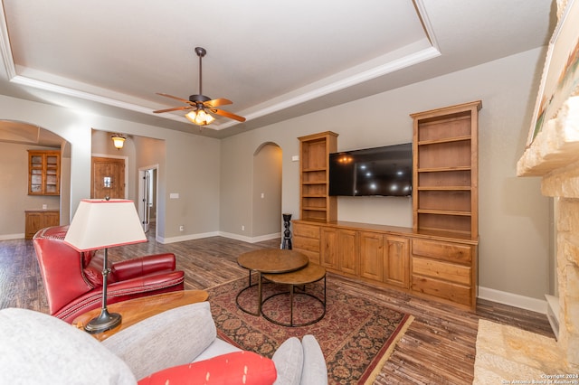 living room with ceiling fan, a raised ceiling, and wood-type flooring