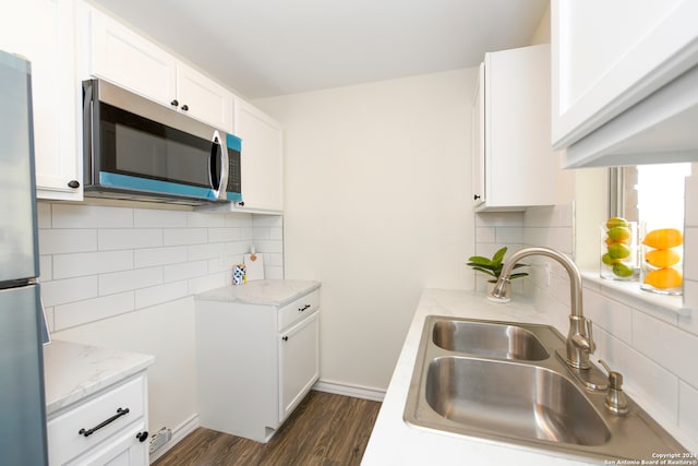 kitchen featuring sink, backsplash, stainless steel appliances, dark wood-type flooring, and white cabinetry