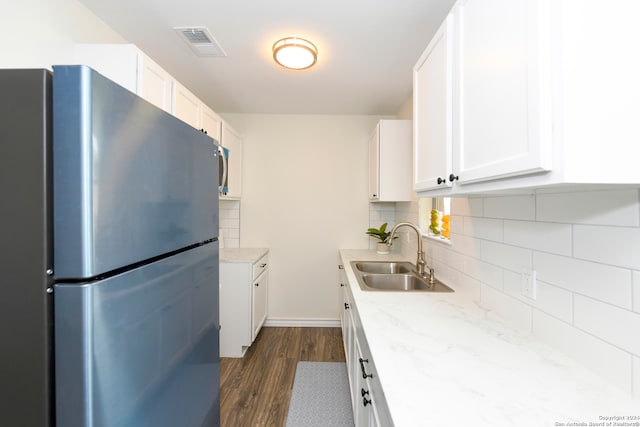 kitchen with backsplash, dark hardwood / wood-style floors, stainless steel fridge, sink, and white cabinets