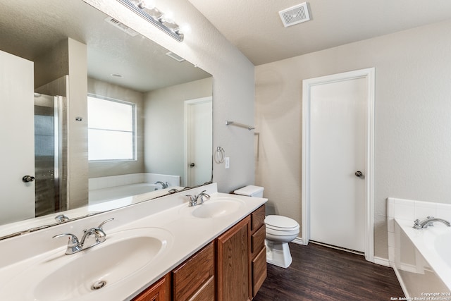 bathroom with a textured ceiling, toilet, hardwood / wood-style flooring, dual vanity, and a washtub