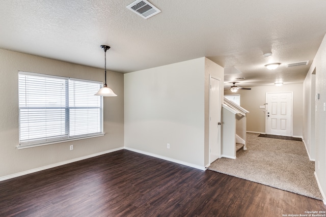 unfurnished room featuring ceiling fan, a textured ceiling, and dark carpet