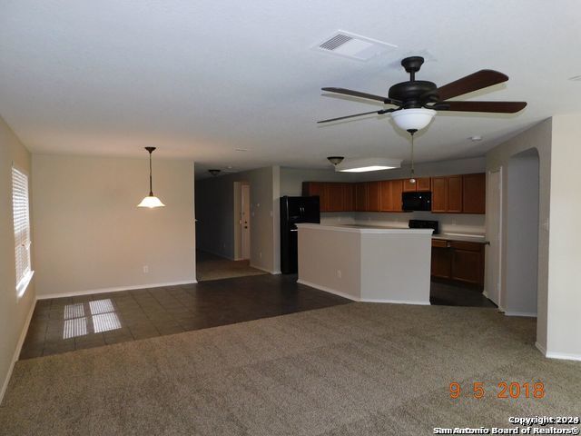 kitchen with ceiling fan, hanging light fixtures, dark colored carpet, and black appliances