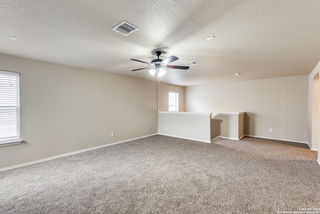 carpeted spare room featuring ceiling fan, plenty of natural light, and a textured ceiling