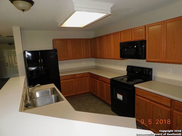 kitchen featuring sink, dark tile floors, and black appliances