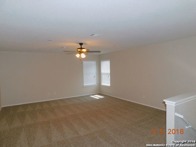 carpeted spare room with ceiling fan