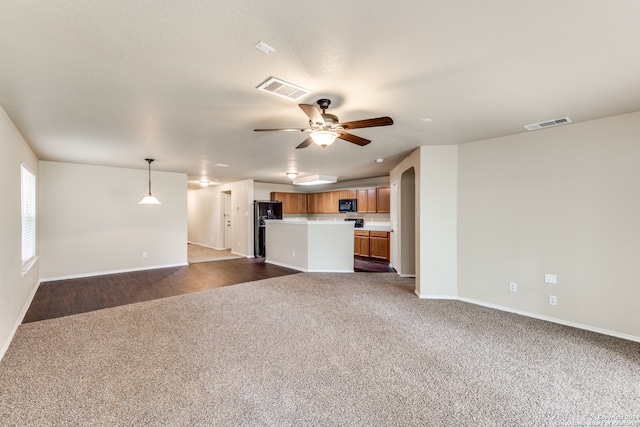 unfurnished living room featuring dark carpet and ceiling fan