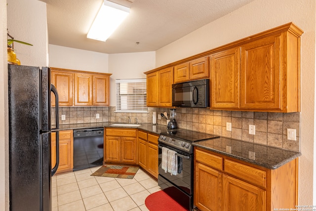 kitchen featuring backsplash, dark stone countertops, light tile floors, and black appliances