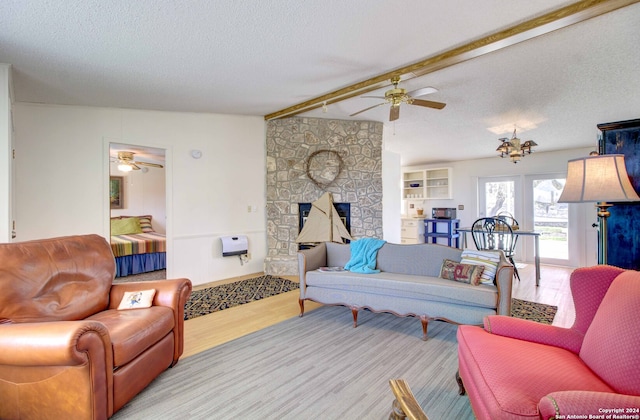 living room with a fireplace, a textured ceiling, light wood-type flooring, and ceiling fan