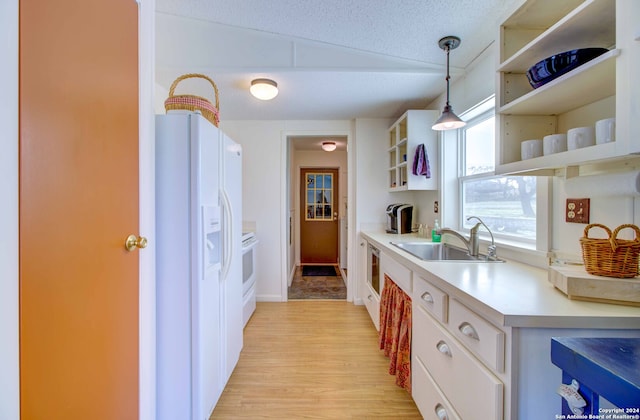 kitchen featuring lofted ceiling, decorative light fixtures, a textured ceiling, white refrigerator with ice dispenser, and sink