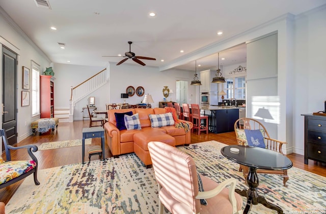 living room featuring ceiling fan, crown molding, and light hardwood / wood-style flooring