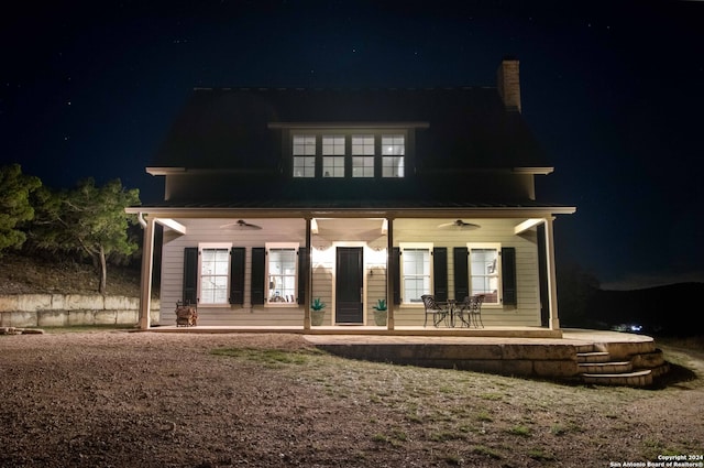 back house at twilight featuring ceiling fan and a patio area