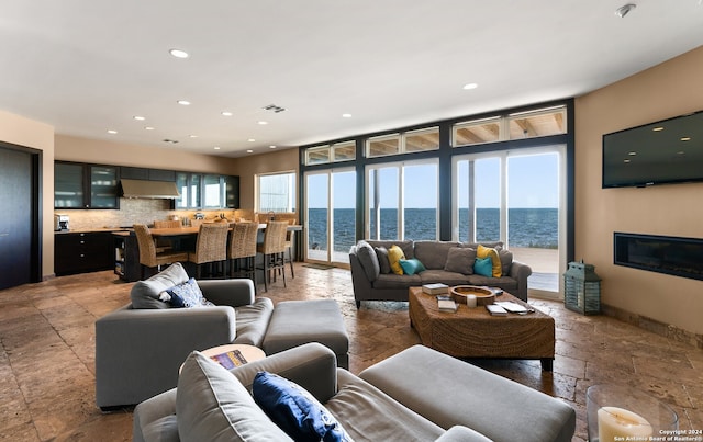 tiled living room with plenty of natural light, a wall of windows, and a water view