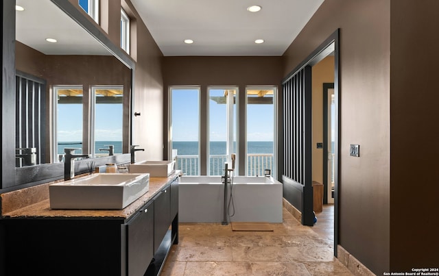 bathroom with a water view, a washtub, double vanity, and french doors