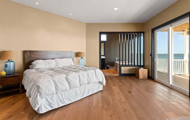 bedroom with a water view, access to exterior, and light wood-type flooring